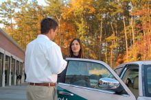 Two people talking outside an open car door